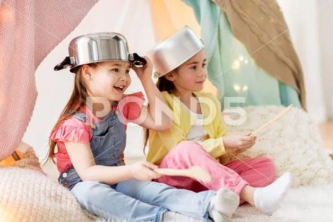 Girls with kitchenware playing in tent at home Stock Photos