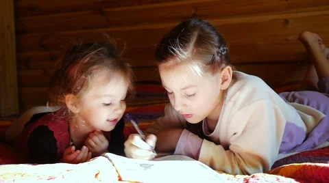 Girls learn to write lying on the bed Stock Footage 54269649