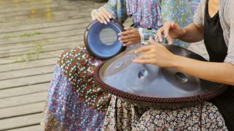 Girls play percussion instruments. Playing music on a djembe and tank drum Stock Footage 153068016