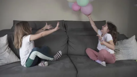 Girls playing with balloons on the sofa Stock Footage 239192971