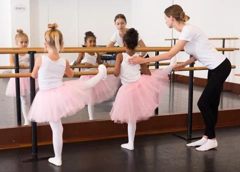 Girls practicing elements on ballet barre Stock Photos