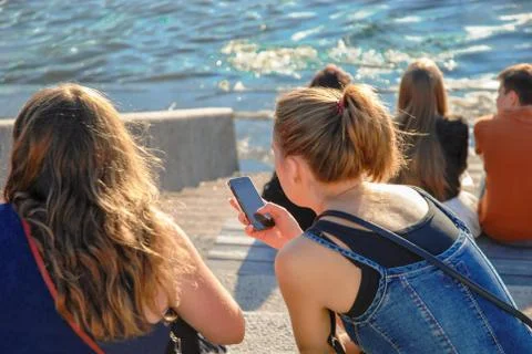 Girls on the river bank with a phone Stock Photos