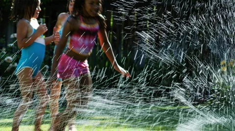 Girls running in a sprinkler Stock Footage