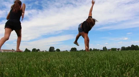 Girls running through the field doing cartwheels and flips Video stock 53769455