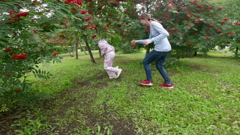 Girls running through park chasing pigeons near rowan trees, playful outdoor Stock Footage 294253445