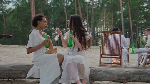 Girls sharing secrets and drinking sitting at the campfire in the woods Vídeo Stock 197171097