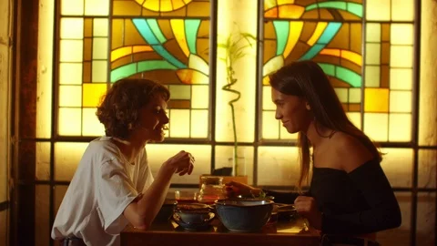 Girls sit at a table in a cafe, one tell a story to another amotionally Stock Footage 121936893