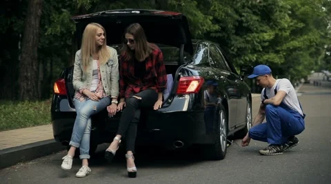 Girls sitting on trunk while mechanic fixes car Stock Footage 65338631