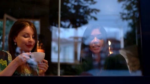 Girls sitting by the window drinking coffee and talking on the phone and with Stock Footage 76711952