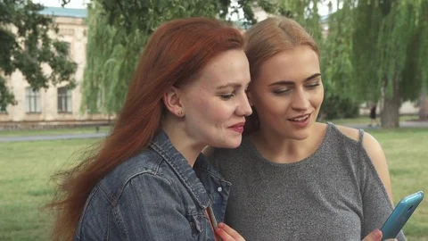 Girls smiling ang talking while sharing the phone Stock Footage 79847803