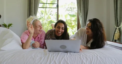 Girls Using Laptop Computer Lying On Bed Laugh Talking, Young Women Group Video stock 81011599