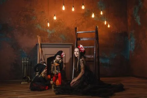 Girls in witch costumes are sitting near the fireplace making a potion, and.. Fotos Stock