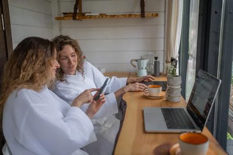 Girls working at laptops at same table distracted by conversation, interesting Stock Photos