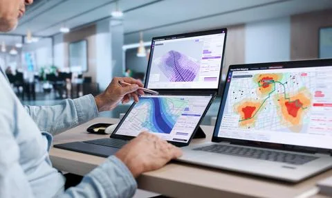 GIS Analyst Examines Flood Risk Data On Dual Touchscreen Laptop For Planning. Stock Photos