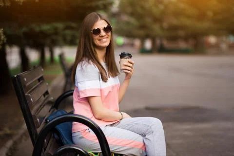 Git in sunglasses sit on bench and drink coffee Stock Photos