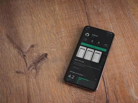 GitHub app play store page on the display of a black mobile smartphone on woo Foto stock