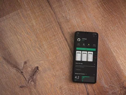 GitHub app play store page on the display of a black mobile smartphone on woo Stock Photos