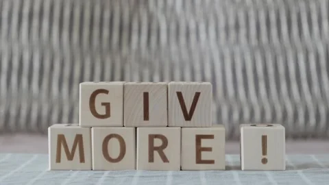 Give more!, laying out  by hand from letters on wooden cubes Stockbeeldmateriaal 342134484