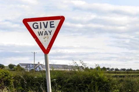 Give way warning red triangle sign with shotgun pellet holes Stock Photos