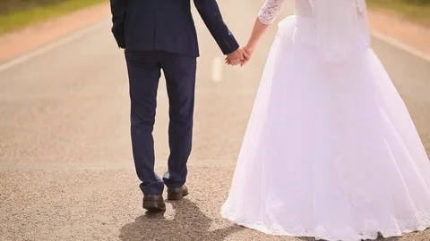 Giving each other the hand of the bride and groom are on the road holding hands Stock Footage 72220449