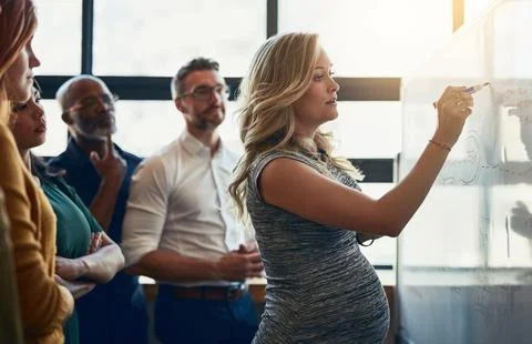 Giving them a practical example. a young pregnant businesswoman giving a Stock Photos