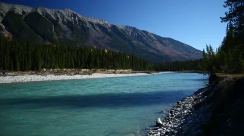 GLACIAL BLUE RIVER FLOWS BY WITH MOUNTAIN IN THE BACKGROUND - 2 Stock Footage 59072459