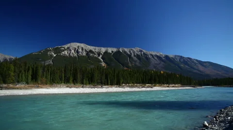 GLACIAL BLUE RIVER FLOWS BY WITH MOUNTAIN IN THE BACKGROUND - 3 Stock Footage 59072461