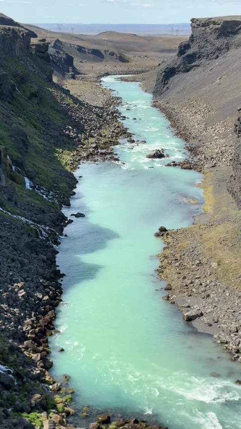 Glacial blue river winds through the rugged lava canyon of Sigöldugljúfur, Icela Stock Footage 312232758