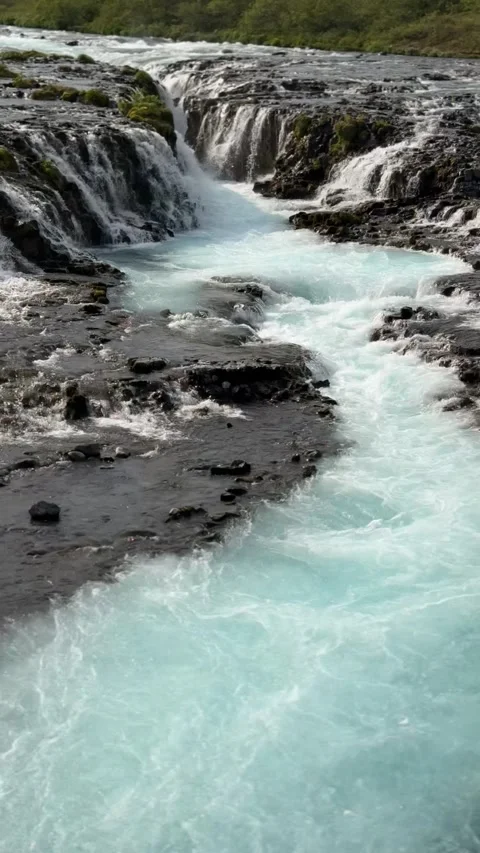 The glacial-fed Brúarfoss waterfall flows over volcanic terrain with surreal blu Stock Footage 312232933
