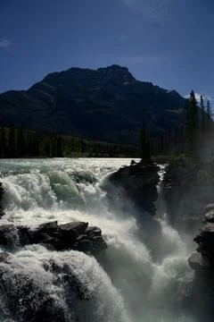 Glacial rapids of Athabasca Falls beneath a massive Rockies summit Stock Photos