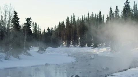 Glacial river streaming through snowy forest with mist flying around, Alaska Видео 129127102