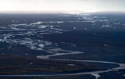 Glacial stream full of meanders reaching the shore Foto stock