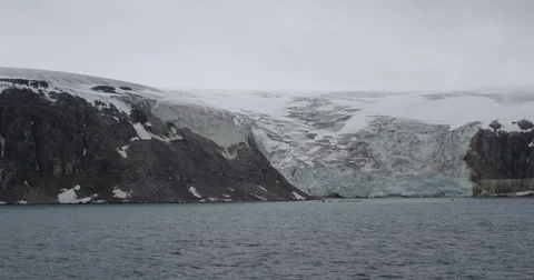 Glacier flows out of snowy mountains into sea Stock Footage 56624408