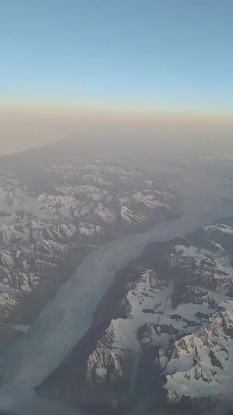 Glacier Flows Through Snow-Covered Mountains Seen From Airplane Window Stock Footage 346346571