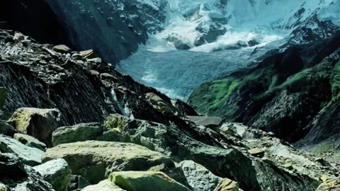 Glacier melting down rocky mountainside with clear blue glacial water flow. Video stock 344244773