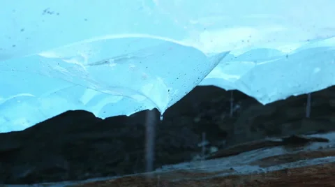 Glacier melting with water dropping down in the blue ice cave Stock Footage 67674467