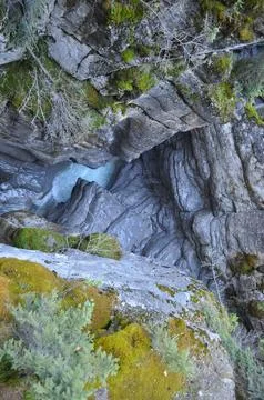 Glacier stream flowing deep down in a rocky canyon Stock Photos