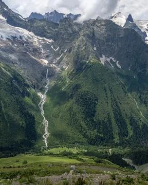 Glacier turning into the river. Mountains in the clouds. Beautiful snow-cappe Stock Photos