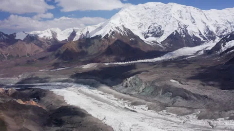 Glacier under Lenin Peak wall with clear sky and mountain peaks in background. E Stock Footage 340086577
