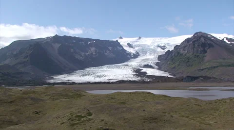 Glacier on volcanic valley with low clouds, moraines and lake in front Stock Footage 37793662