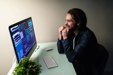Glad bearded man programer working on computer with win gesture 스톡 사진