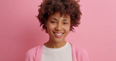 Glad dark skinned Afro Ammerican woman has tender expression smiles gently shows Stock Footage 142753480