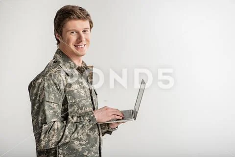 Glad male soldier surfing the internet Stock Photos