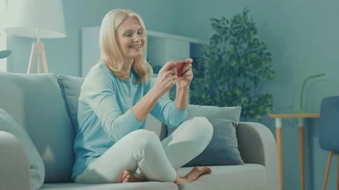 Glad positive old lady sit couch play telephone videogame Stock Footage 166903158