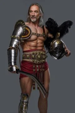 Gladiator of mature age dons lightweight armor, wielding a gladius Stock Photos
