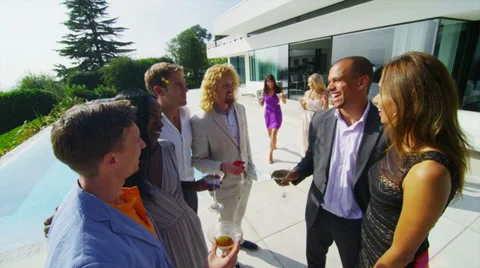 Glamorous friends enjoying drinks by the pool outside luxury modern home Video stock 32886844