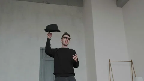 Glamorous handsome guy in stylish black sunglasses dancing with mans hat, moves Stock Footage 107814893