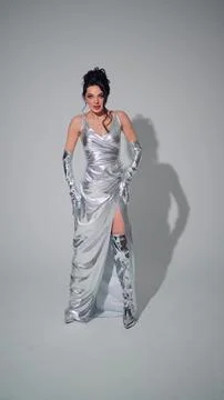 Glamorous model poses in the studio in a silver dress Stock Photos