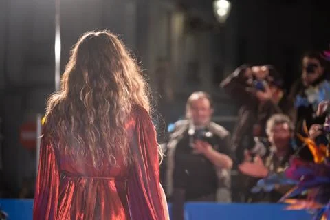 Glamorous Model Strutting in Shiny Red Outfit on Runway Photos
