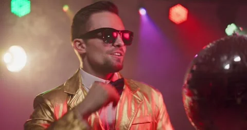Glamorous performer in gold jacket dancing by disco ball on nightclub stage Stock Footage 327527091